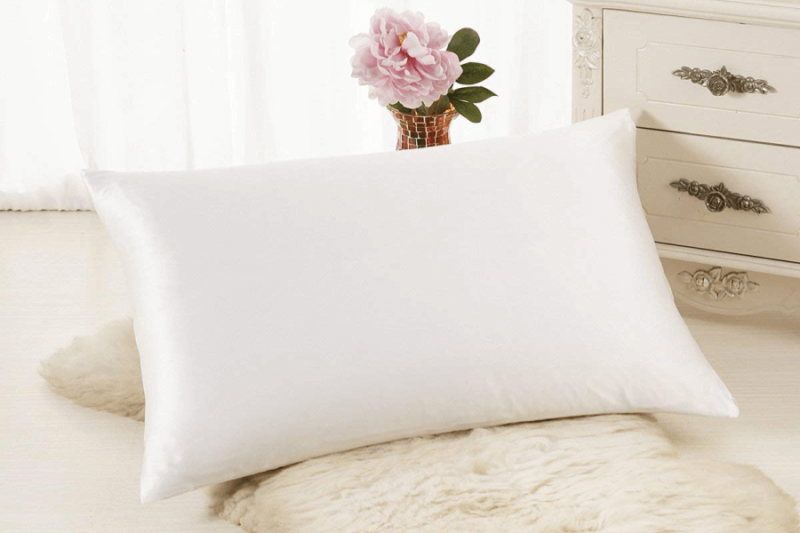 white ALASKA BEAR Silk Pillowcase resting on white fur rug and against gold vase with flower in it
