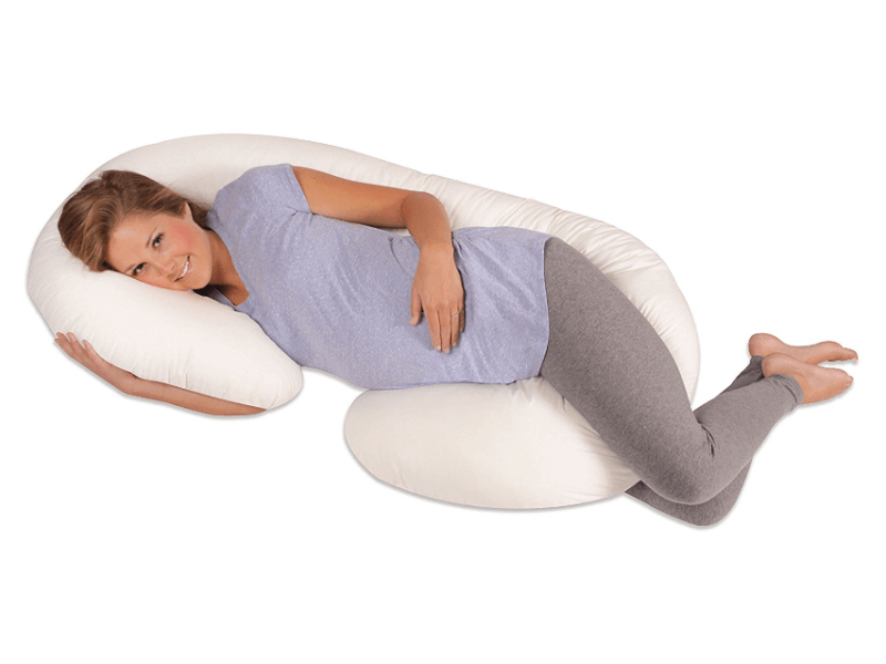 pregnant woman using c-shaped body pillow while lying on her side