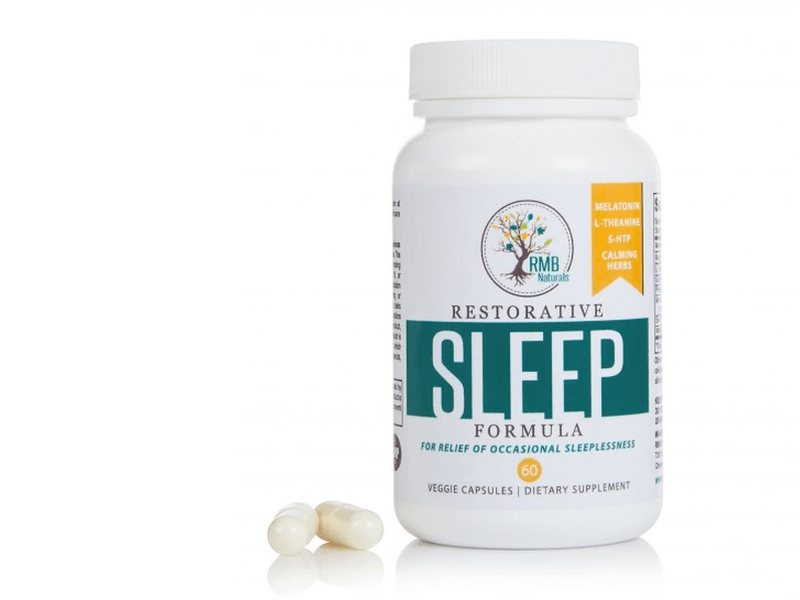 front of RMB Naturals Restorative Sleep Formula bottle with two capsules next to it on white background
