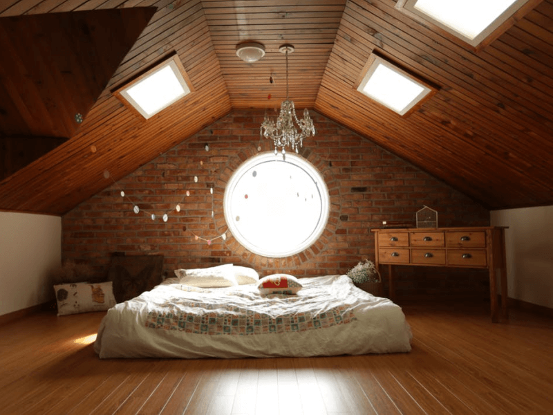bed laid directly on wooden attic floor underneath a chandelier