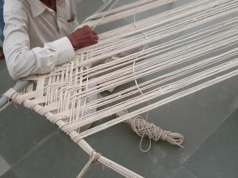 man weaving rope to make a charpai