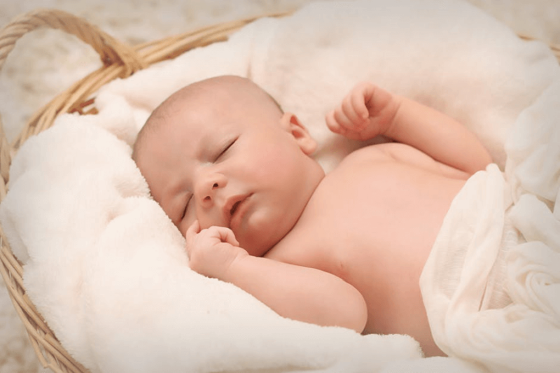 A baby sleeping soundly on a fluffy fabric, inside a basket