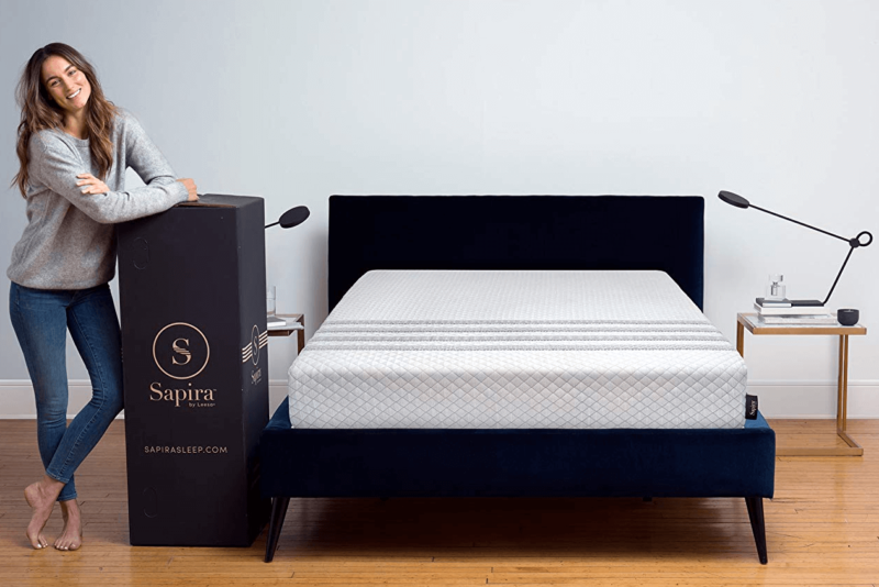 Leesa Sapira mattress on black bed frame next to woman and delivery box