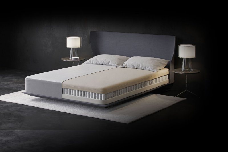 Eight Mars+ smart mattress on white rug between two bedside tables with a lamp on top of each, mattress interior shown