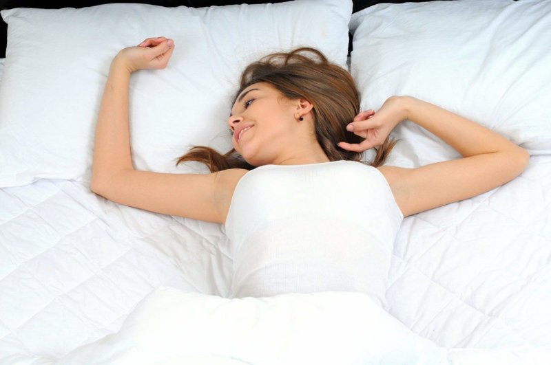 Woman lying on top of bed covered by Utopia Bedding mattress pad
