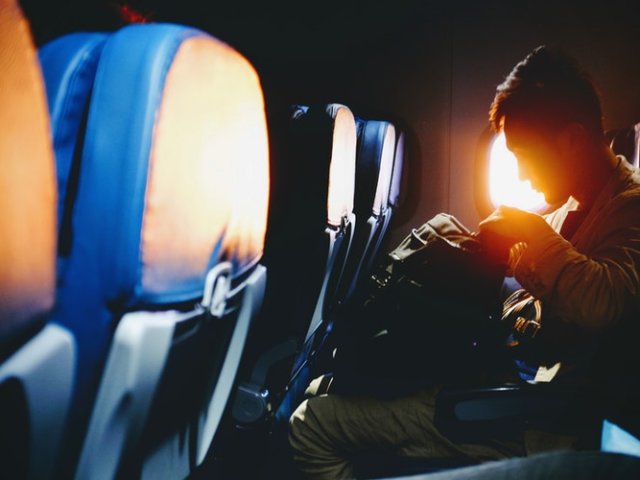 Person looking through their bag while sitting on the window seat of a plane